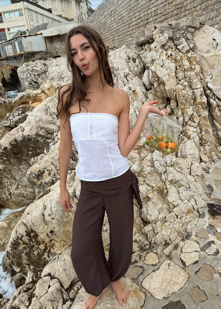 Pantalón largo pareo marrón con lazo en la cintura y caída holgada sobre rocas