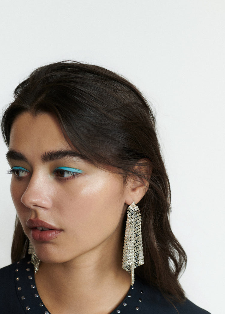 Pendientes de malla metálica en forma de rombo de color plata vistos en perfil sobre modelo