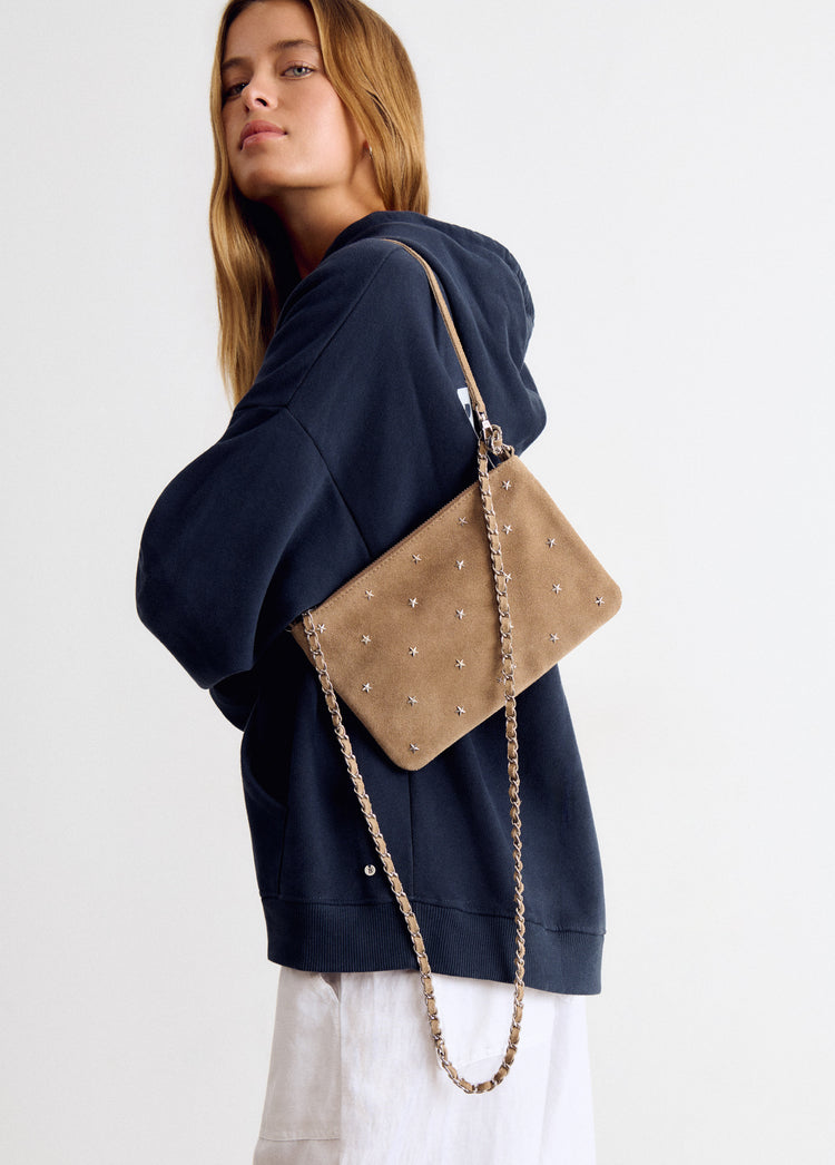 Bolso de cuero taupe con solapa y cadena dorada colgado sobre modelo