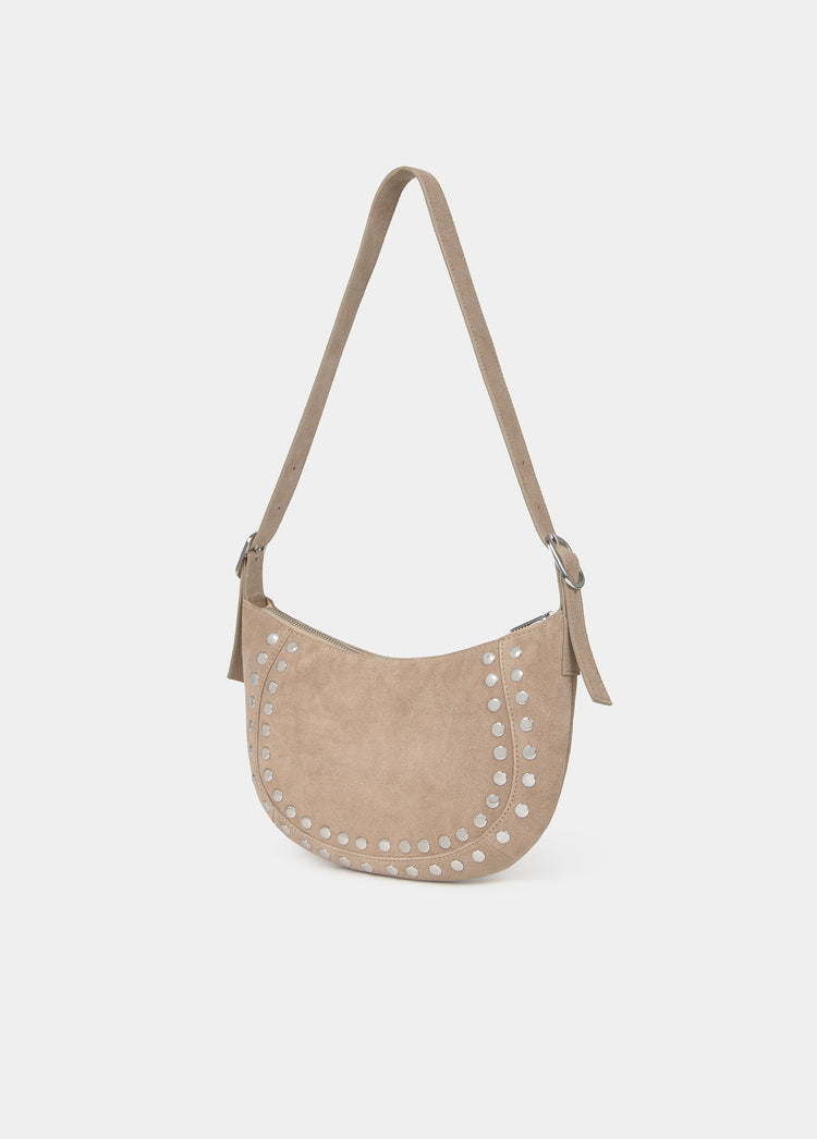 Bolso de media luna en taupe claro con remates de tachas plateadas y correa larga ajustable
