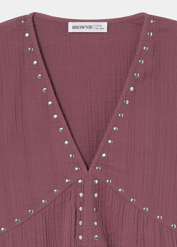 Blusa de manga larga en tono rosado con escote en V y remates de tachas metálicas