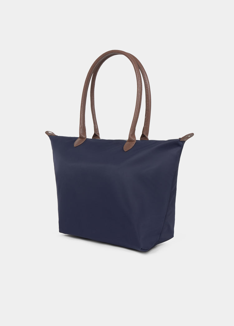 Bolso shopper de nylon azul marino con asas de piel marrón visto de perfil