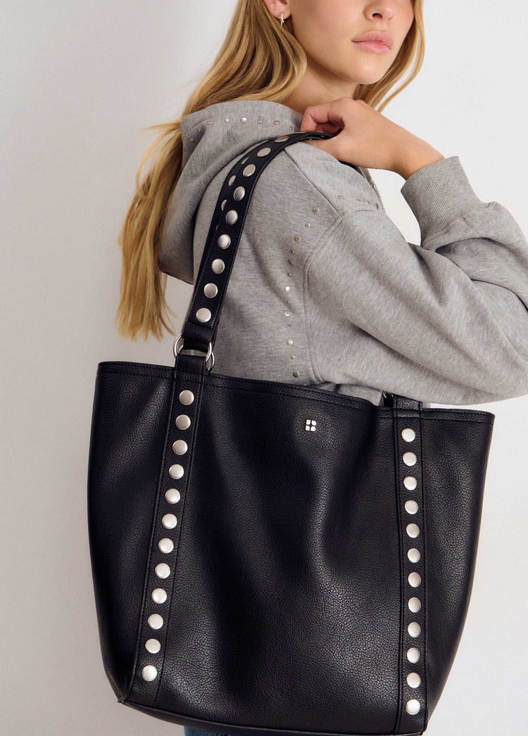 Bolso shopper negro con tachas plateadas luciendo su asa y perfil lateral