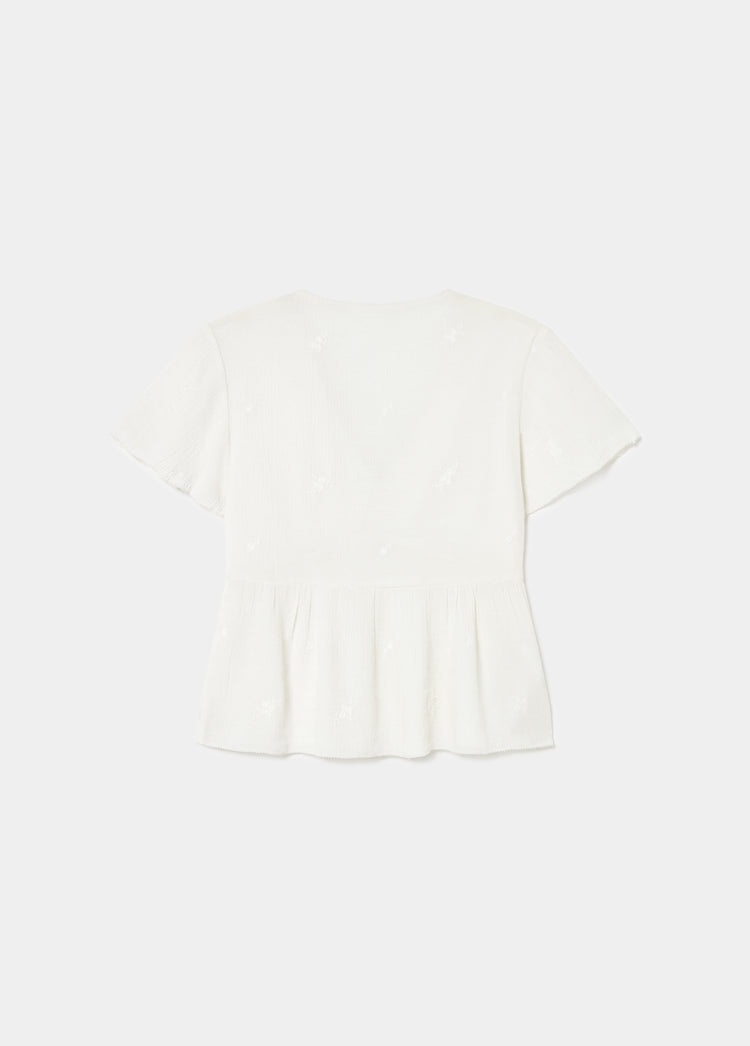 Blusa de manga corta con volantes en color crudo vista por la espalda sobre fondo liso