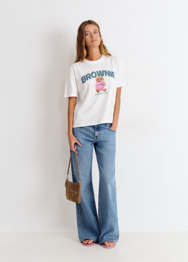 Camiseta blanca de manga corta con estampado de perrito y la palabra brownie sobre modelo