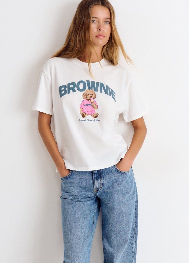 Camiseta blanca de manga corta con estampado de perrito y la palabra brownie sobre modelo