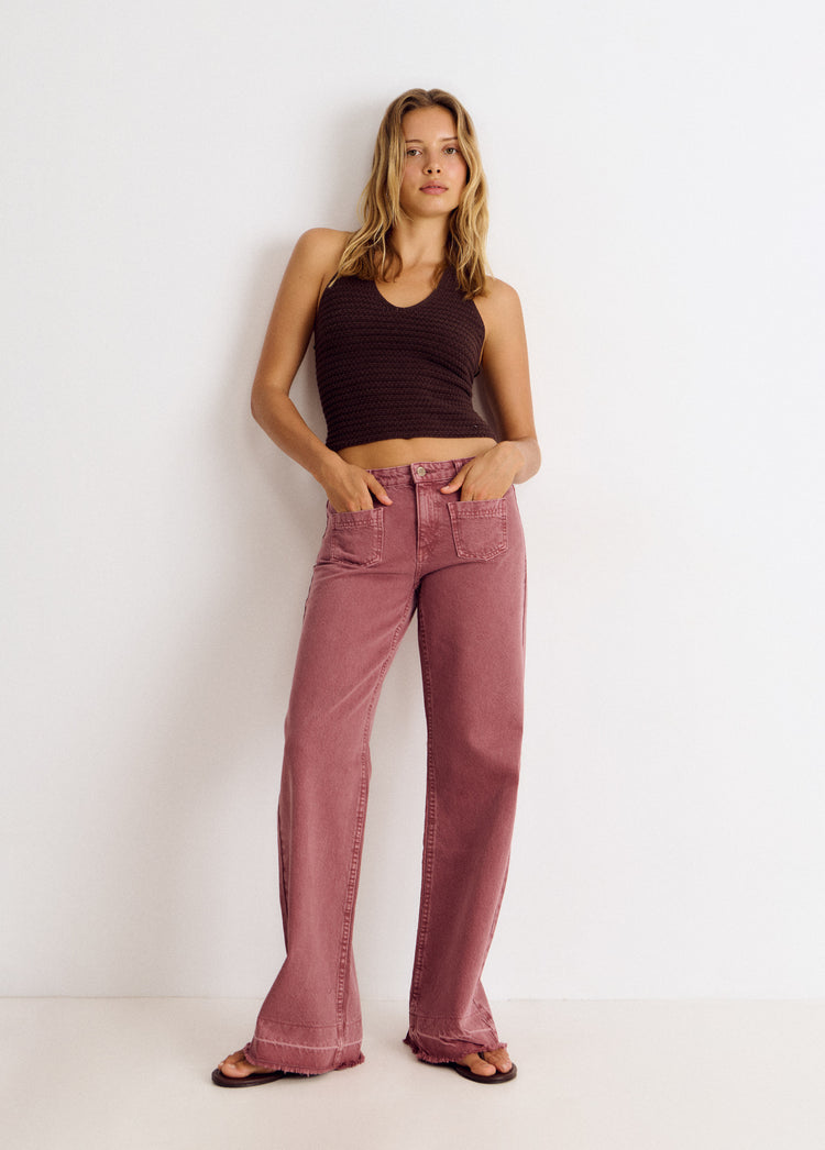 Pantalón vaquero de pierna ancha en tono rosado con bolsillos frontales sobre modelo