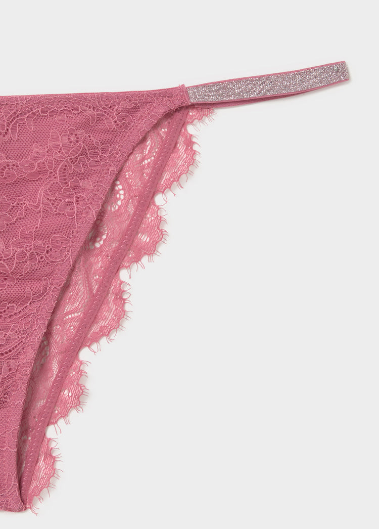 Braguita de encaje rosa con tirante lateral brillante y borde festoneado en primer plano