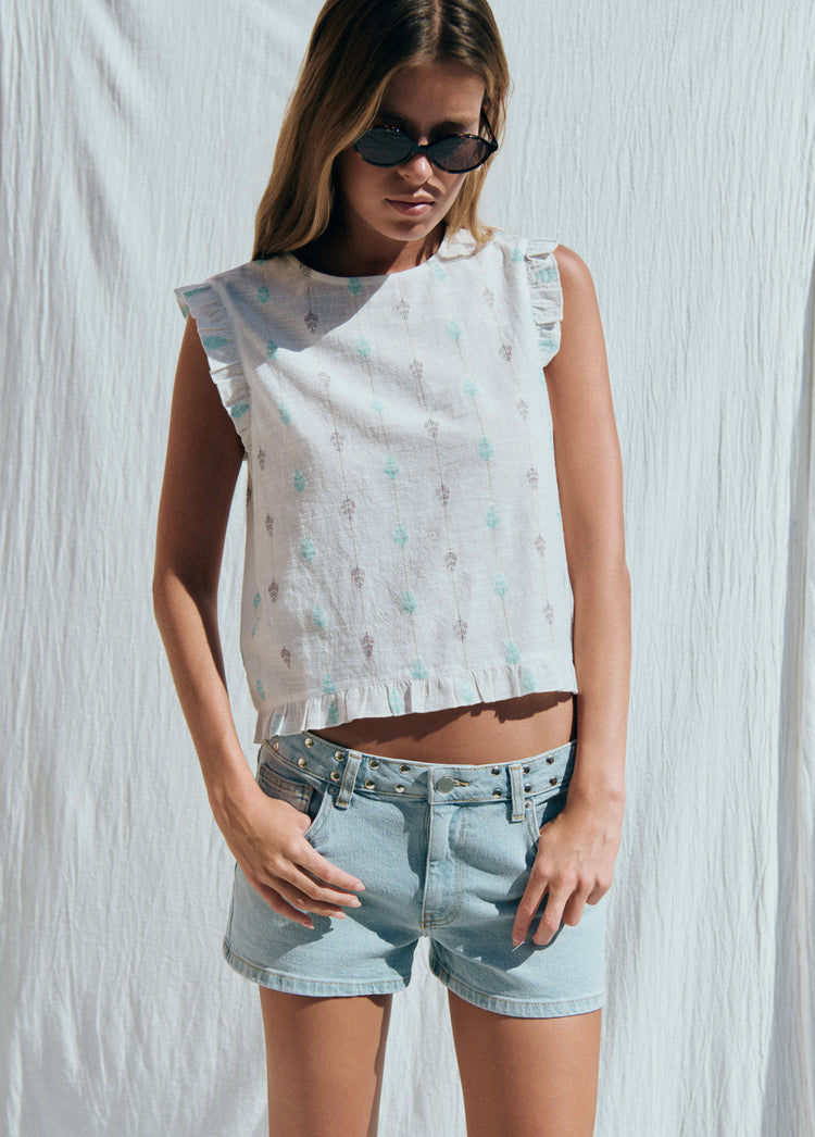 Blusa multiposición de color blanco con bordado floral y volantes en los bordes