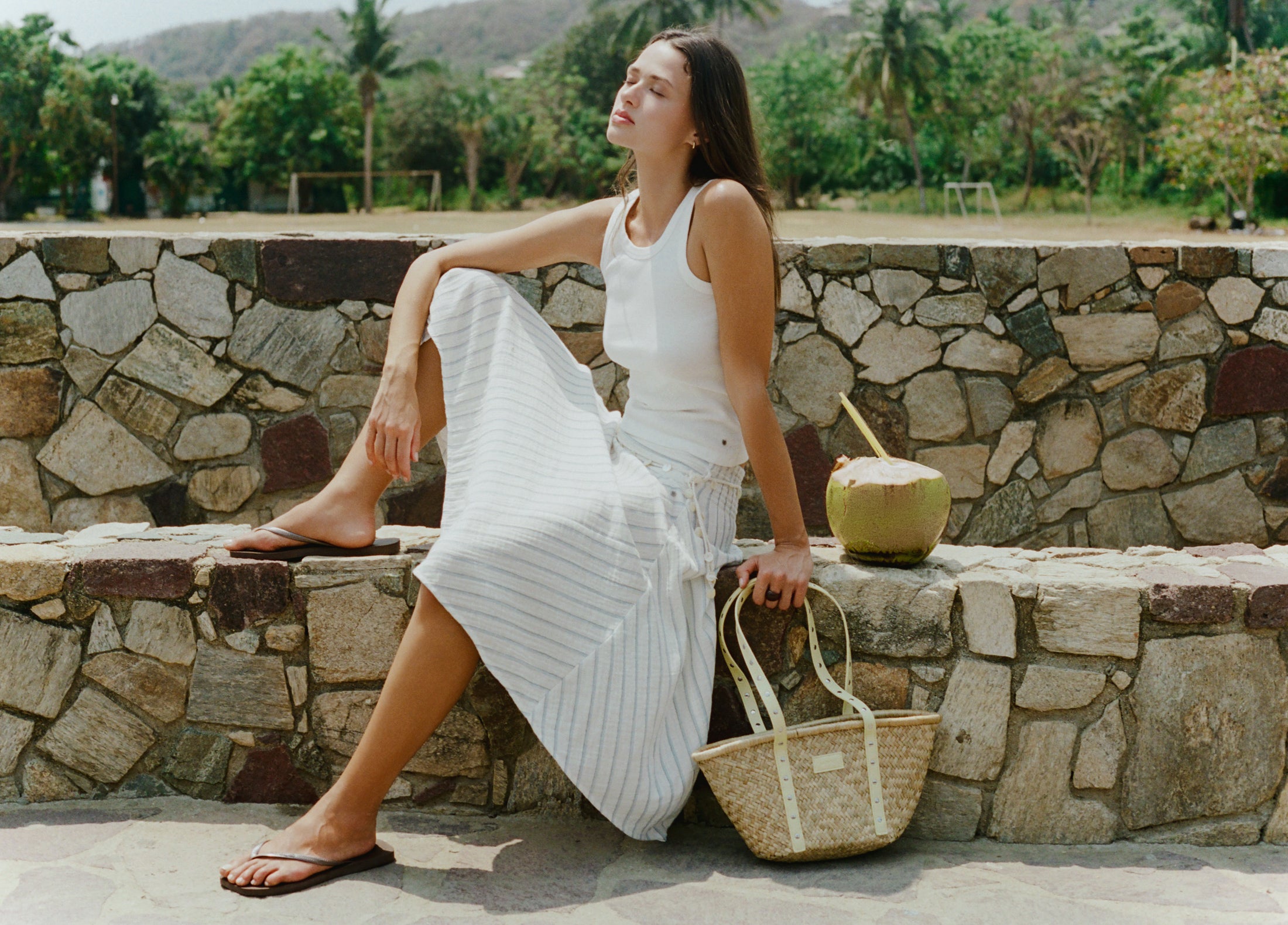 Bolso capazo de mimbre en tono natural con tiras de cuero perforado y detalles metálicos