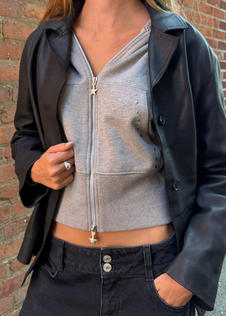Sudadera gris de cremallera frontal con detalle de tachas en el pecho y capucha