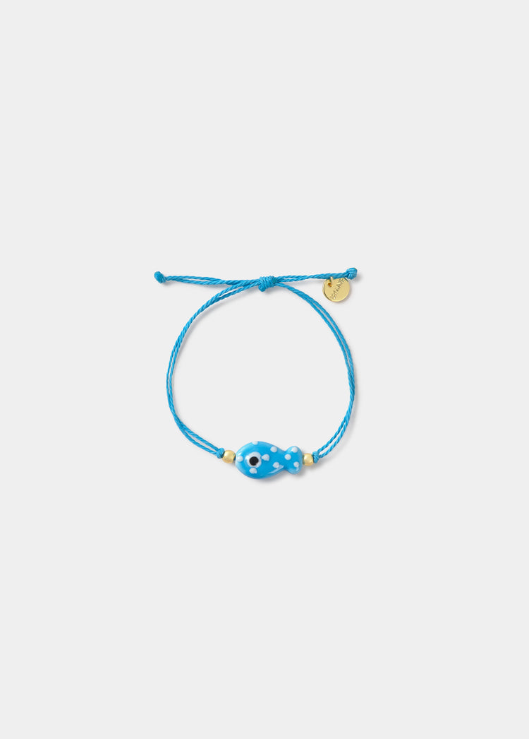 Pulsera de hilo azul con colgante de pez y detalles dorados sobre fondo liso