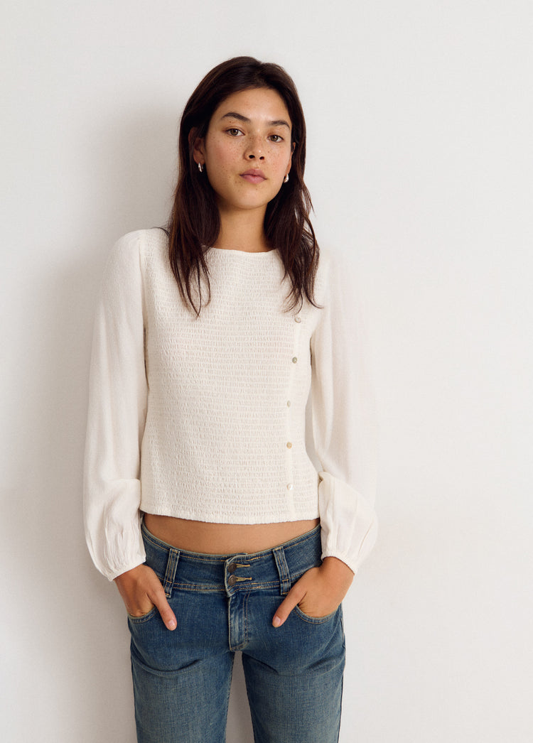 Blusa blanca de manga larga con efecto smock y botones frontales vista de frente