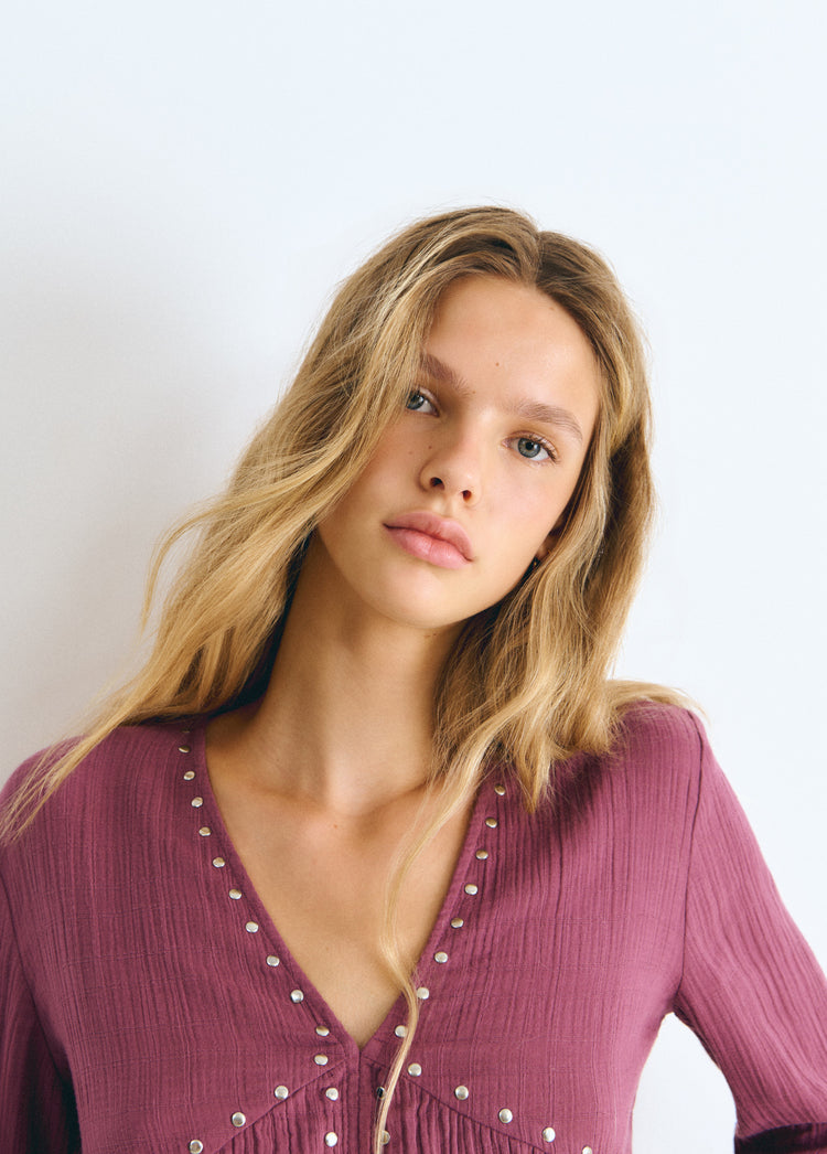 Blusa de manga larga en tono rosado con escote en V y remates de tachas plateadas