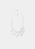 Collar doble de plata con colgantes de estrellas lucido sobre el escote drapeado