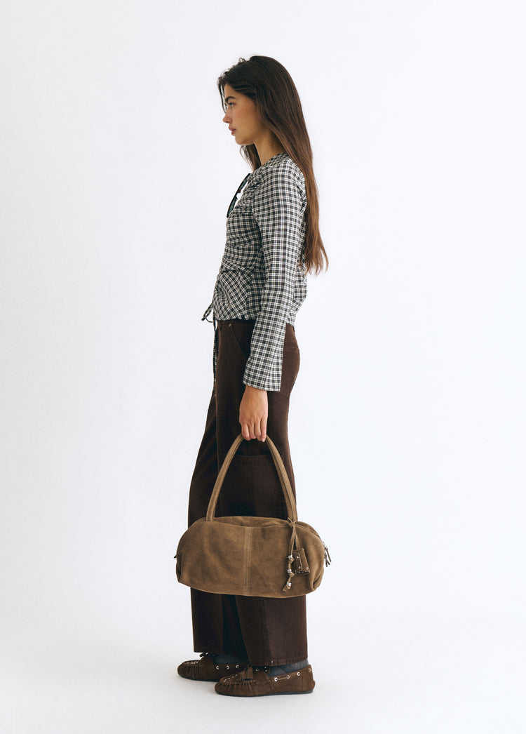 Bolso baguette de color taupe visto de perfil sobre modelo