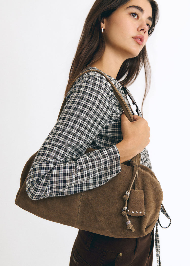 Bolso baguette de color taupe luciendo sus charms sobre modelo