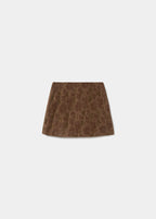 Falda mini de flores en tono terracota vista de perfil sobre una silla de madera