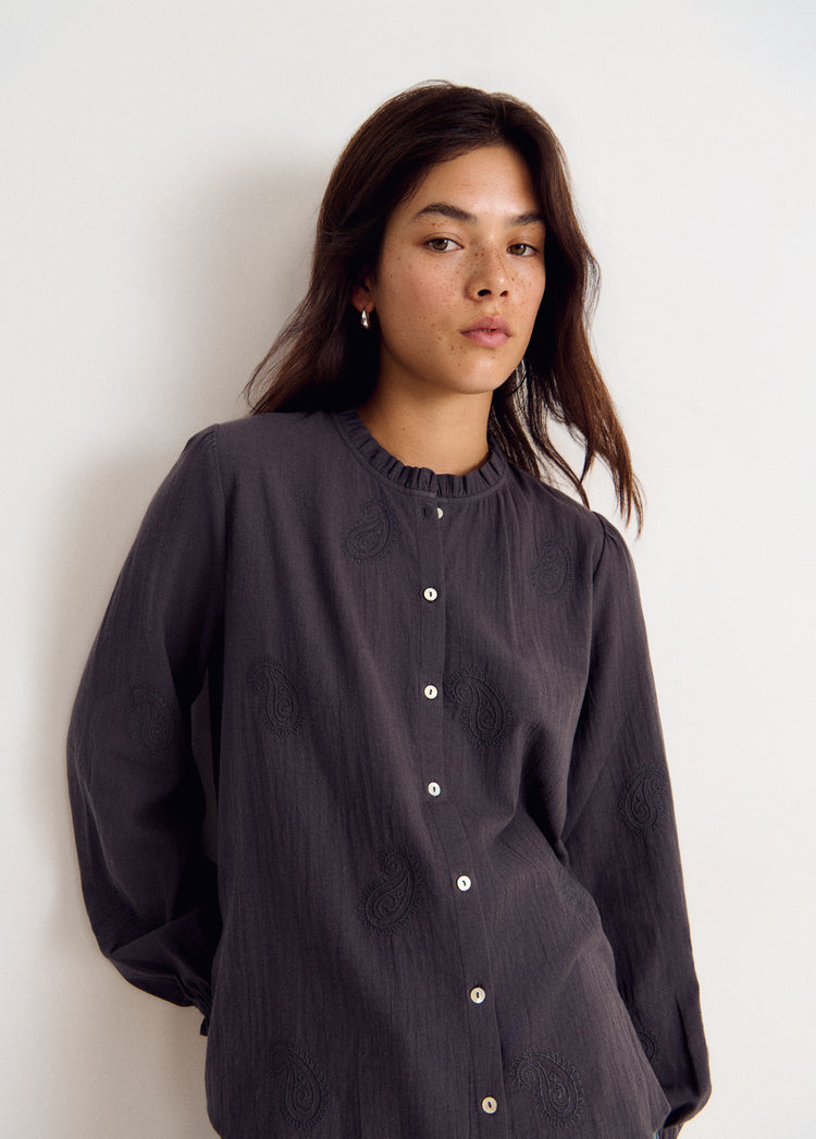 Blusa de manga larga en gris con bordados sutiles y botones frontales vistos de frente