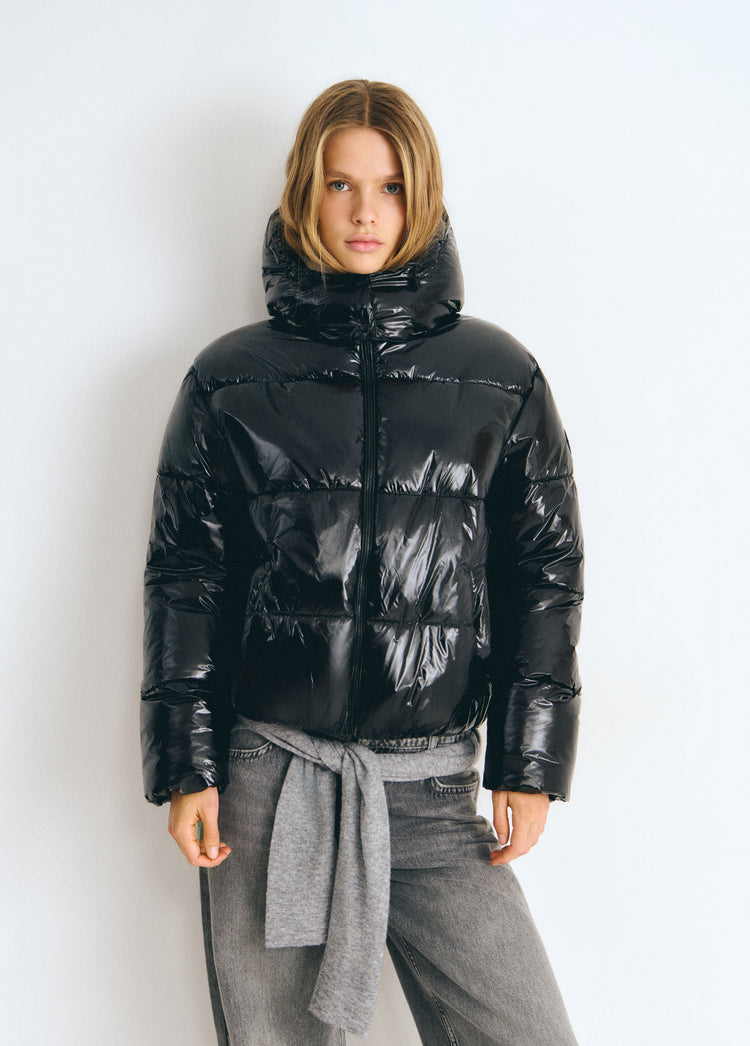 Chaqueta acolchada de vinilo negro con capucha y cremallera frontal vista de frente
