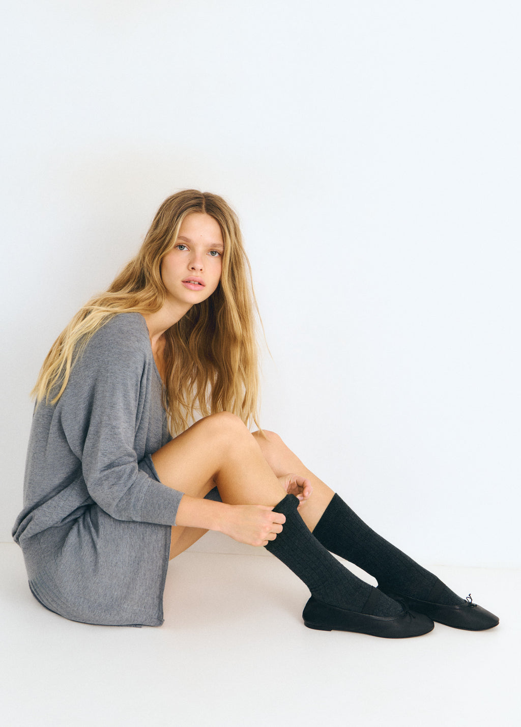 Bailarina de piel negra vista lateral con calcetines negros y jersey gris