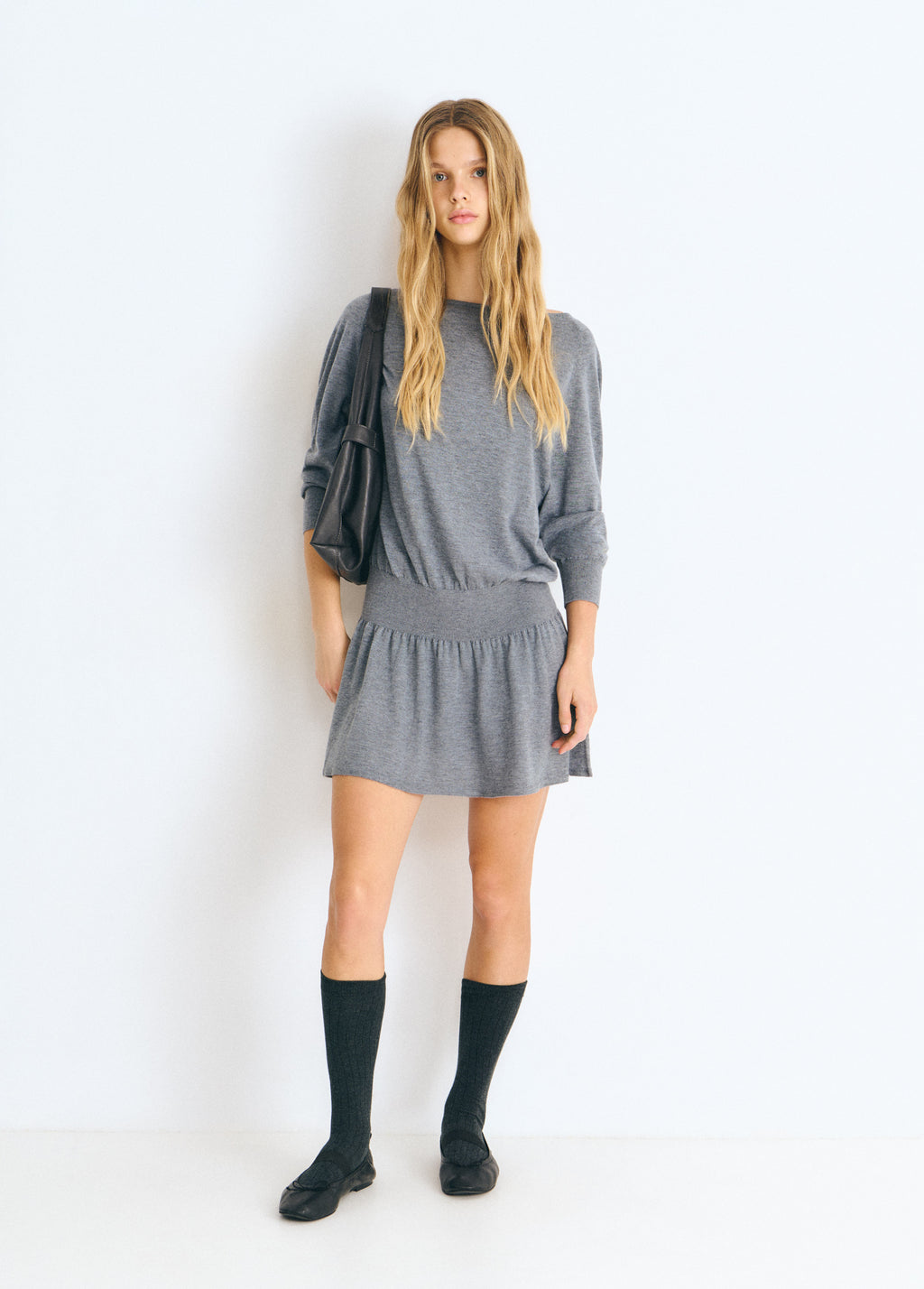 Vestido de jersey gris con cuello redondo y falda plisada visto de frente