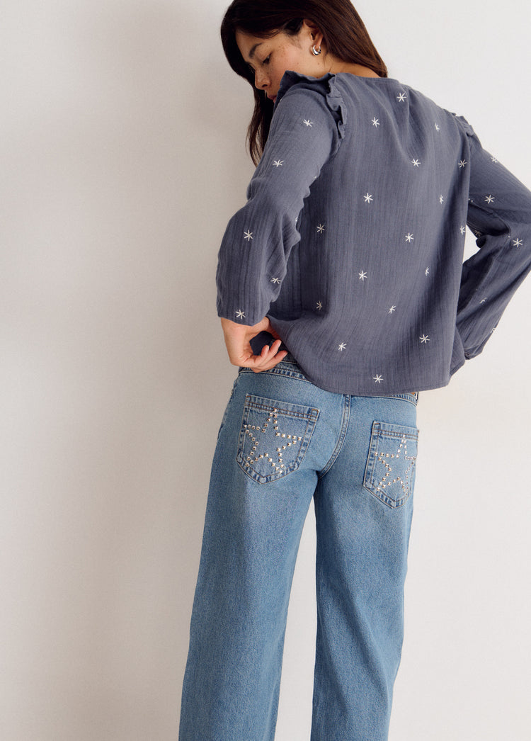 Blusa de manga larga en azul con estampado de estrellas y escote pico vista desde la espalda