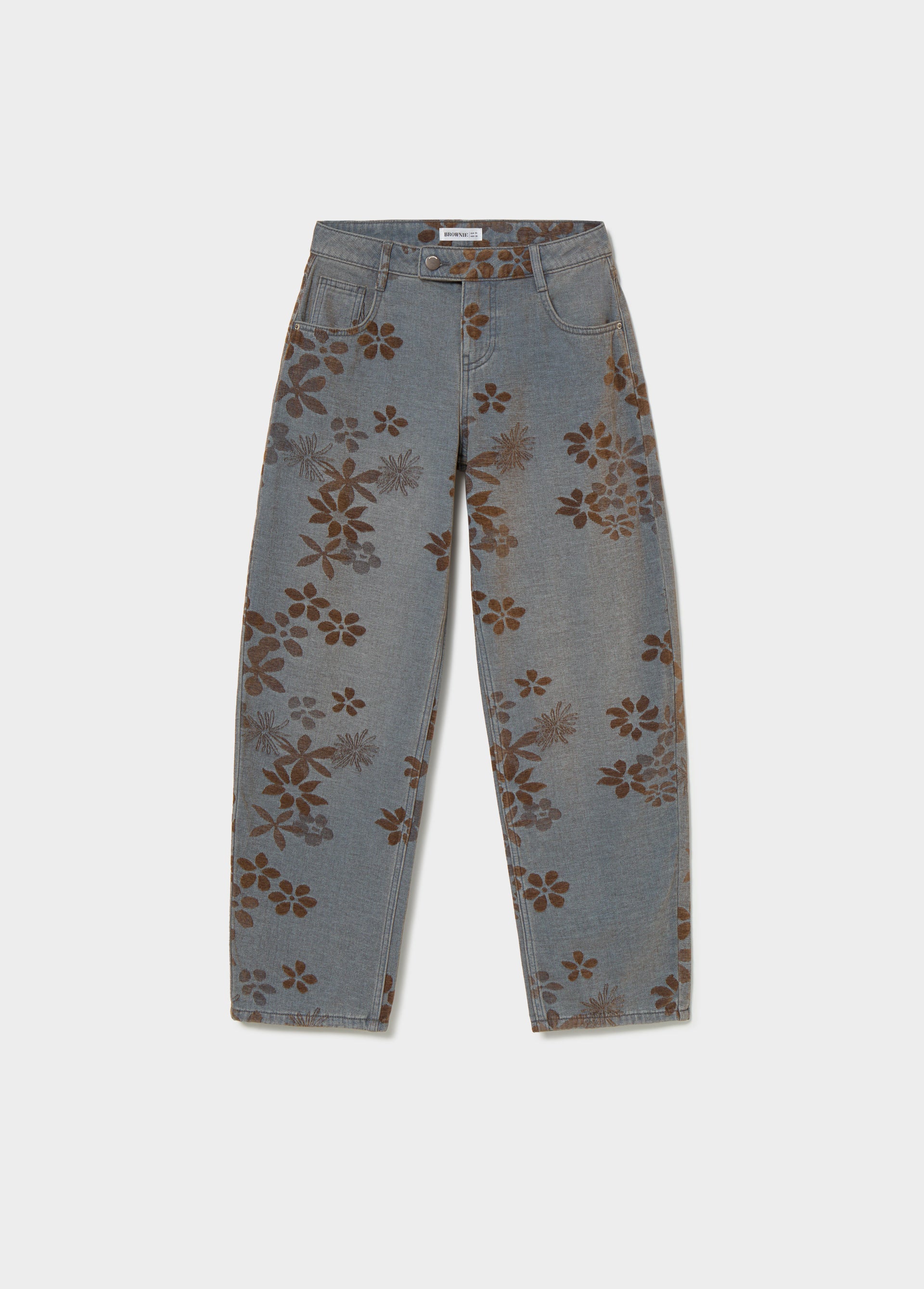 Vaqueros de jacquard floral en azul medio vistos de perfil sobre un mueble negro