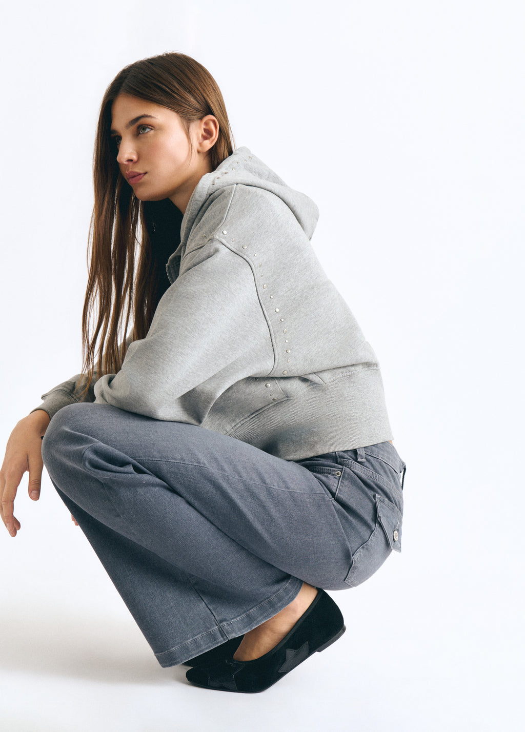 Jeans flare de gris vistos de perfil sobre modelo con sudadera